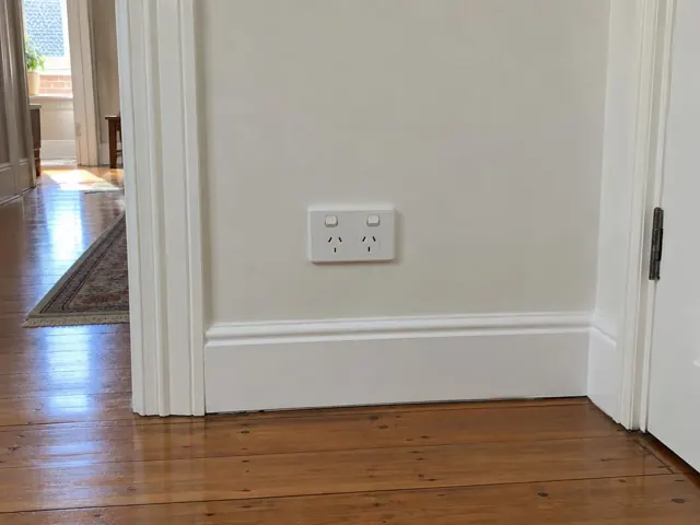 White double power point on a painted hallway wall above timber floorboards in North Sydney