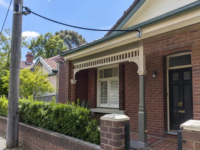 Overhead service cable and bracket on a brick house facade with porch in Wollstonecraft
